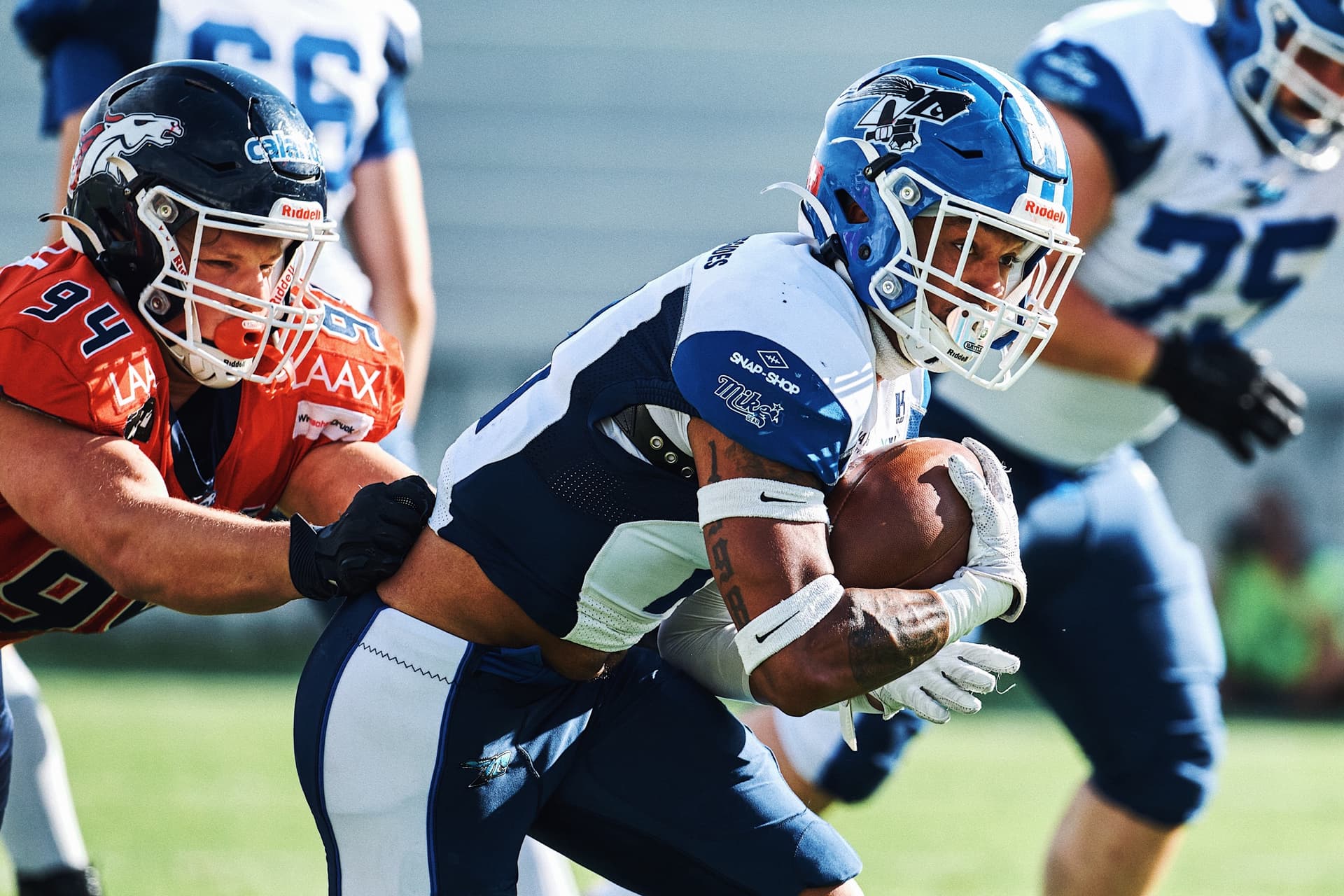 Football player carrying the ball through a tackle